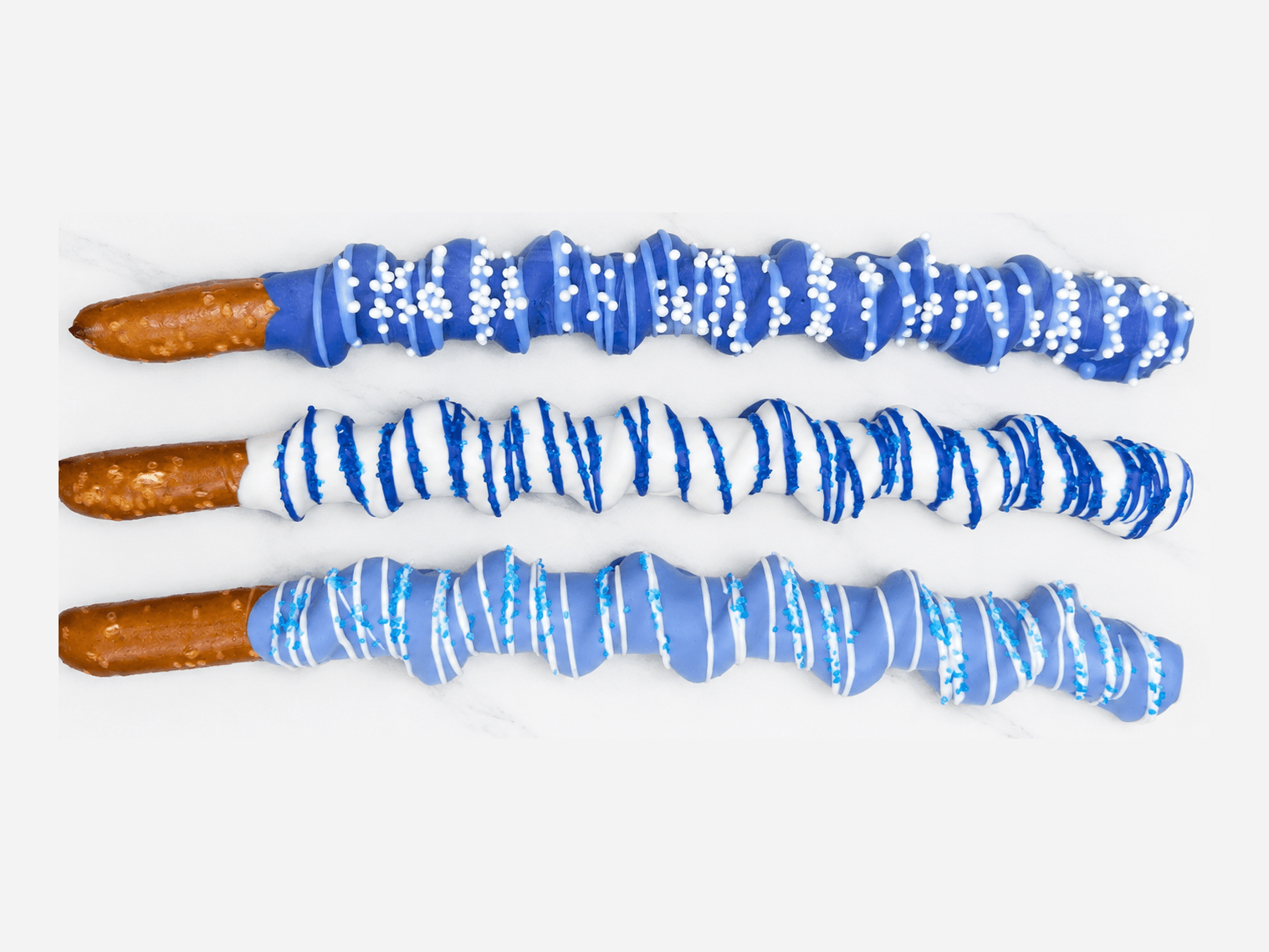Periwinkle blue chocolate-dipped pretzel rods with white and blue sprinkle designs