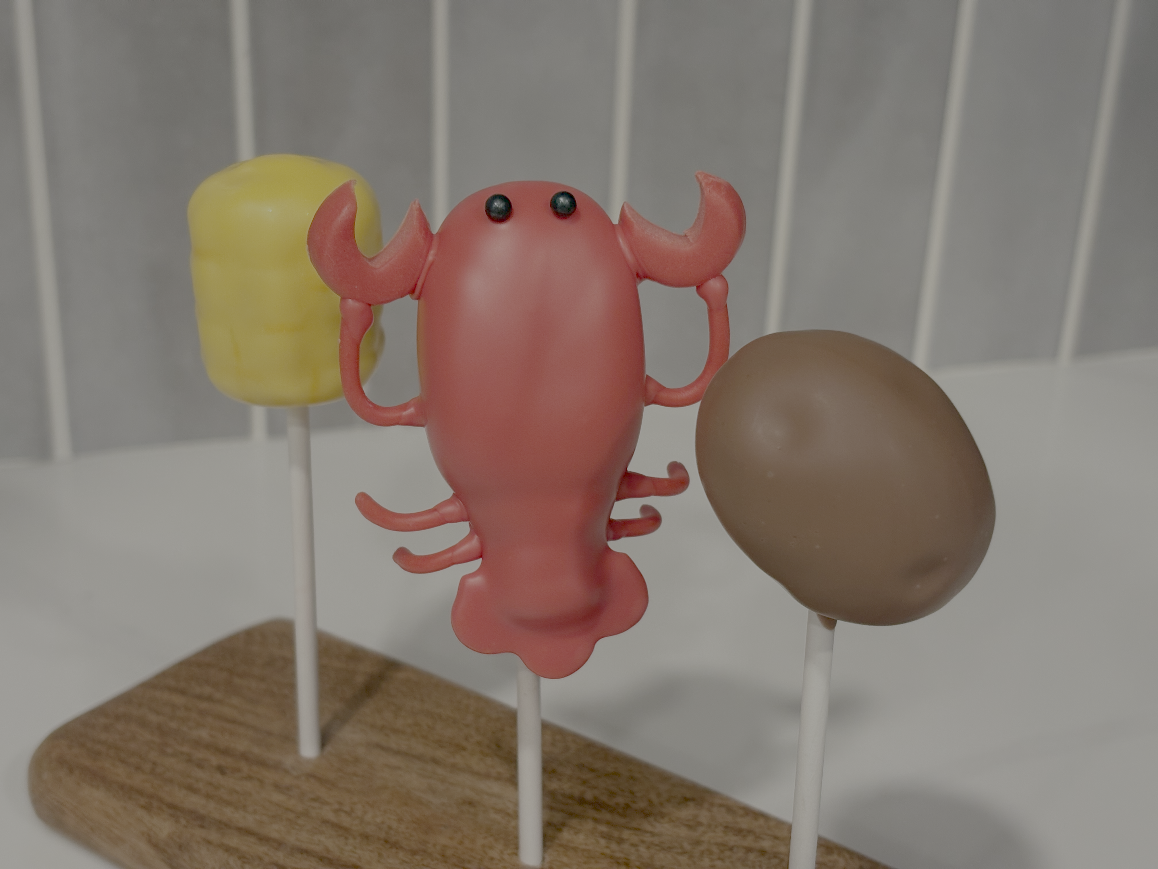 Louisiana-themed cake pops shaped like a crawfish, an ear of corn, and a potato