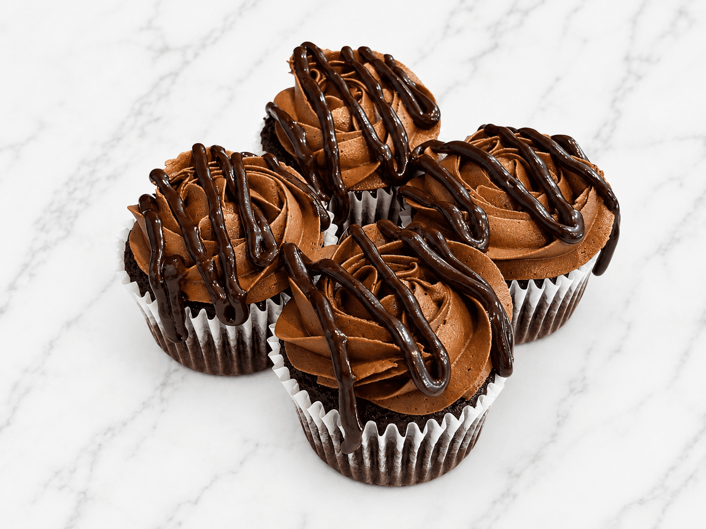 Chocolate cupcakes topped with piped chocolate buttercream and a chocolate ganache drizzle