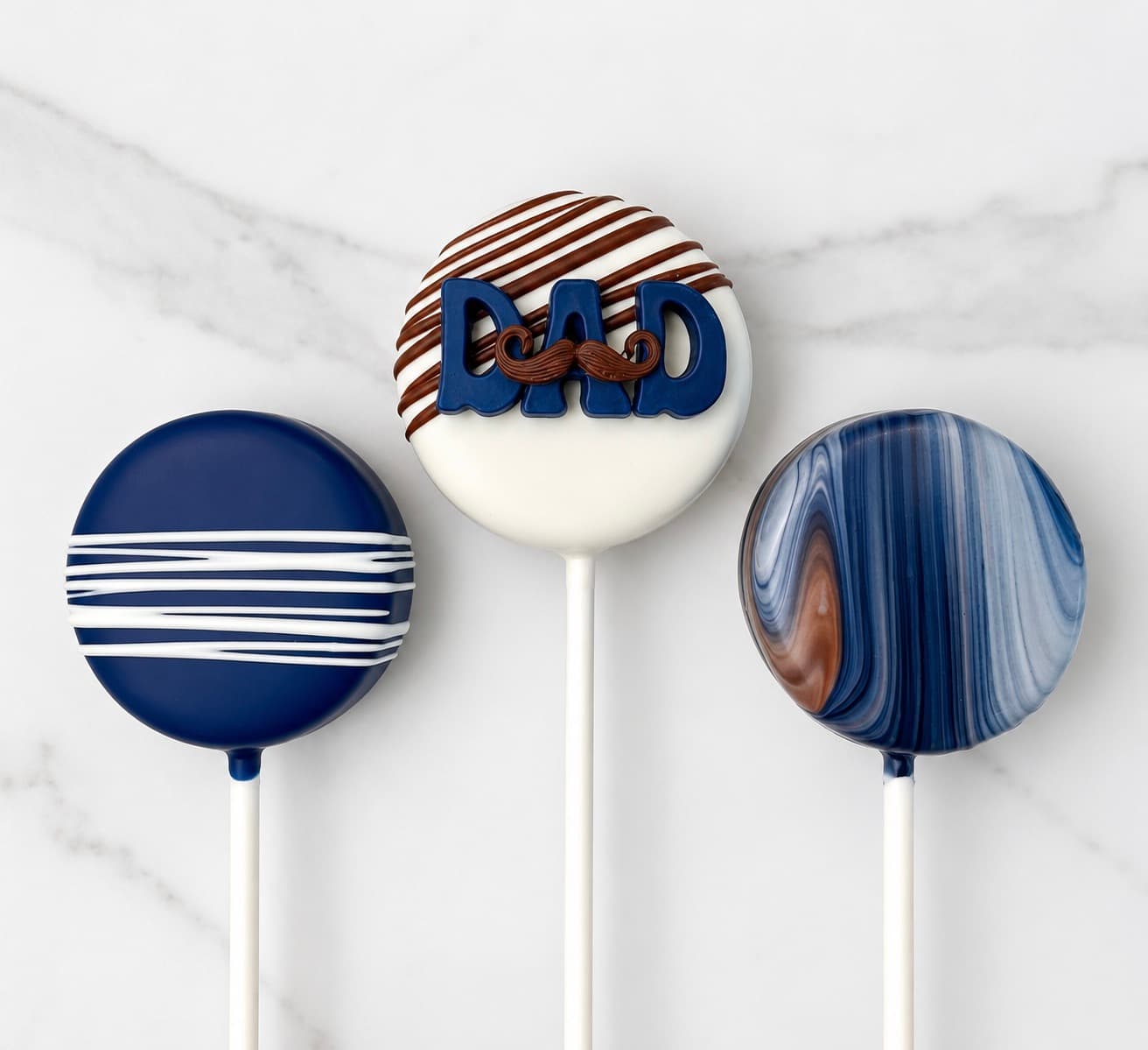 Navy blue and marbled cake pops spelling out 'DAD'