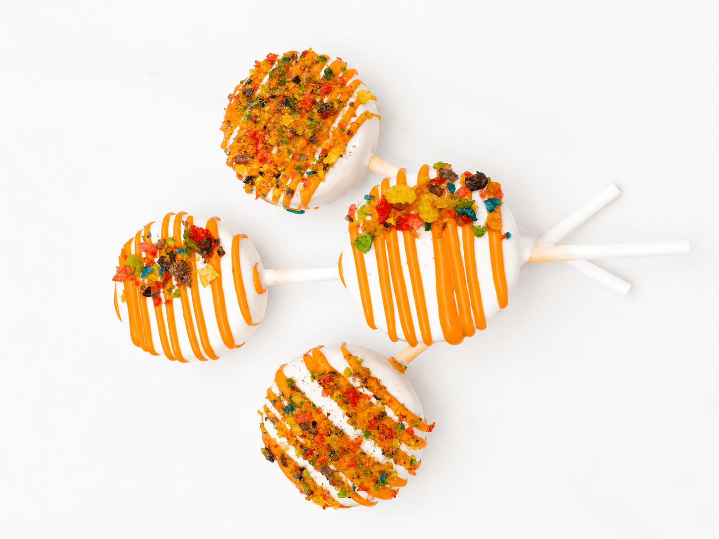 Round cake pops coated in white chocolate and topped with colorful fruity cereal crumbs