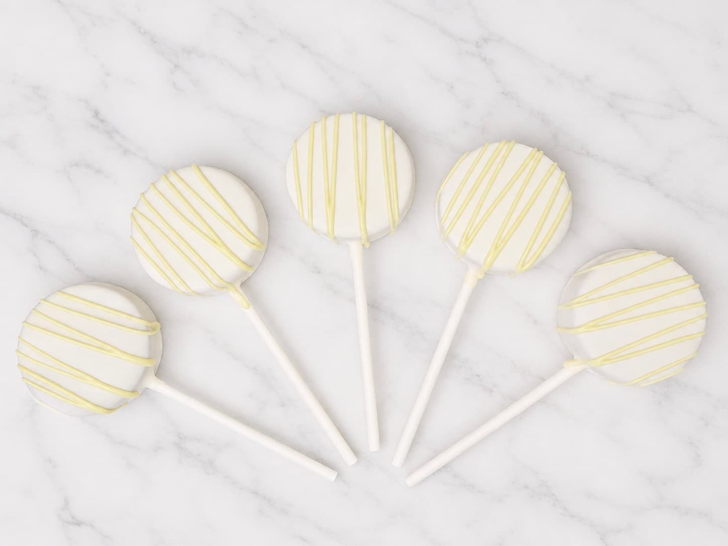 Cake pops dipped in white chocolate with pale matcha-green drizzle